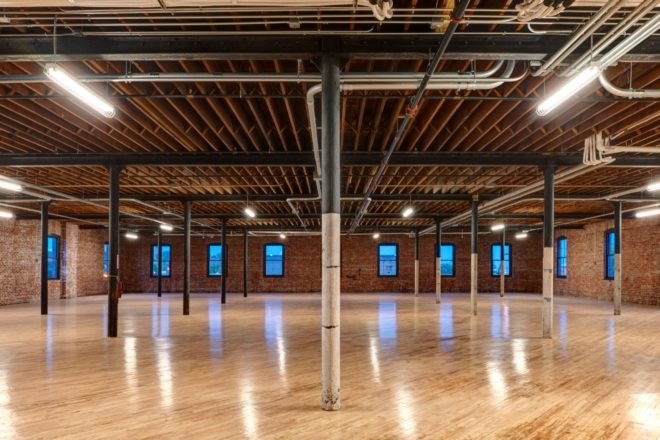 open floor space in renovated warehouse with light wood floors and brick walls