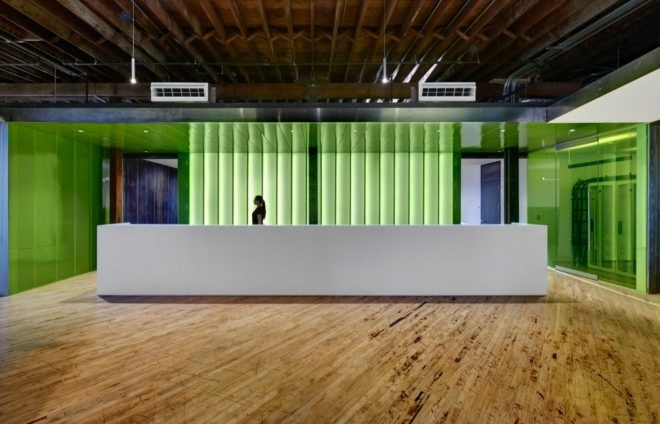 reception area with long white desk and green translucent walls