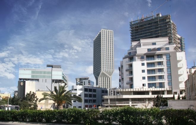 view of tall white twisting tower from the street below