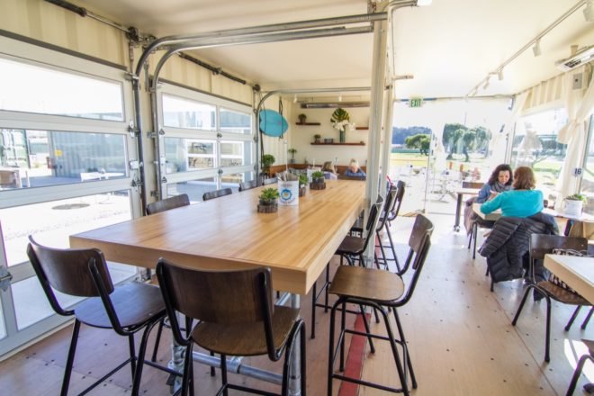 indoor dining area with long light wood table and several smaller surrounding tables
