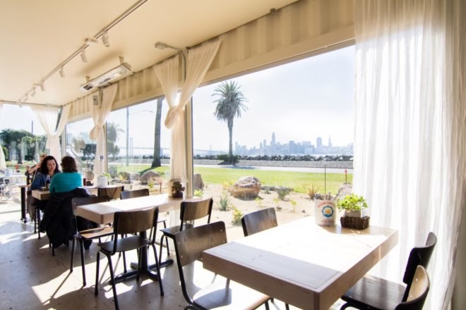 light wood tables and dark wood chairs in front of large glazed windows