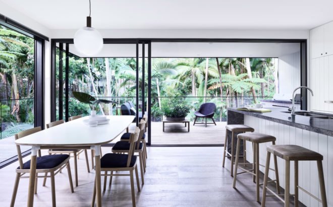 Open kitchen and dining space with large white dining table and glass walls