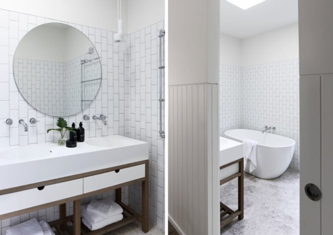 On the left, white bathroom with subway tiles and round mirror. On the right, free standing tub.