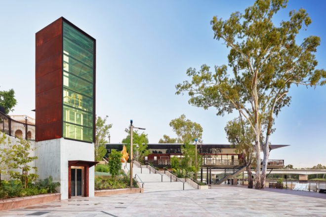 Long riverside pier with glass walls and nearby structure with concrete and Corten steel exterior