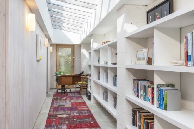 White wall with large built-in bookshelves fille diwth books and writing desk at the end of the wall