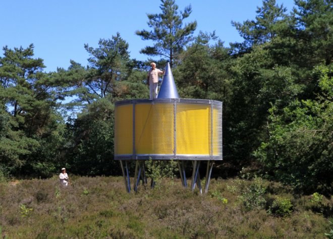 round yellow pavilion on metal supports in forest landscape