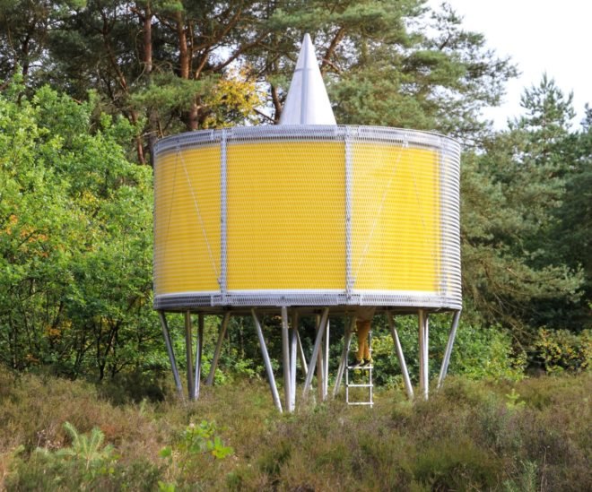 round yellow pavilion on metal supports in forest landscape