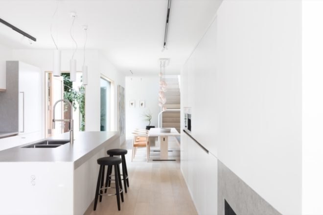 white kitchen island with black bar stools and dining table in the background