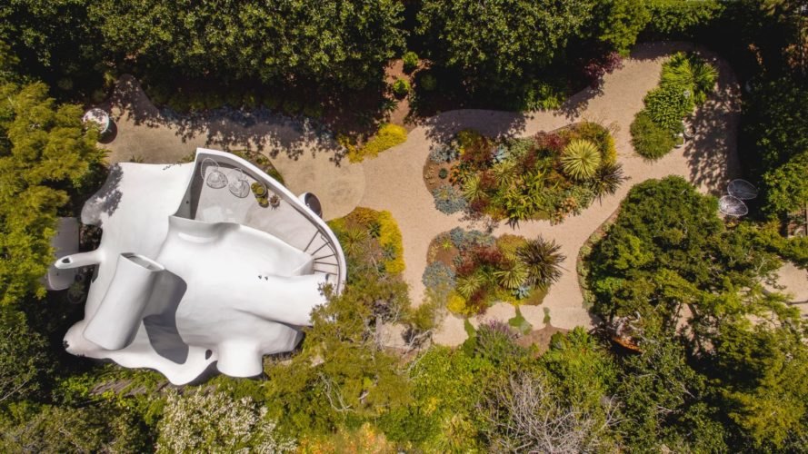 an aerial shot of a white structure surrounded by greenery