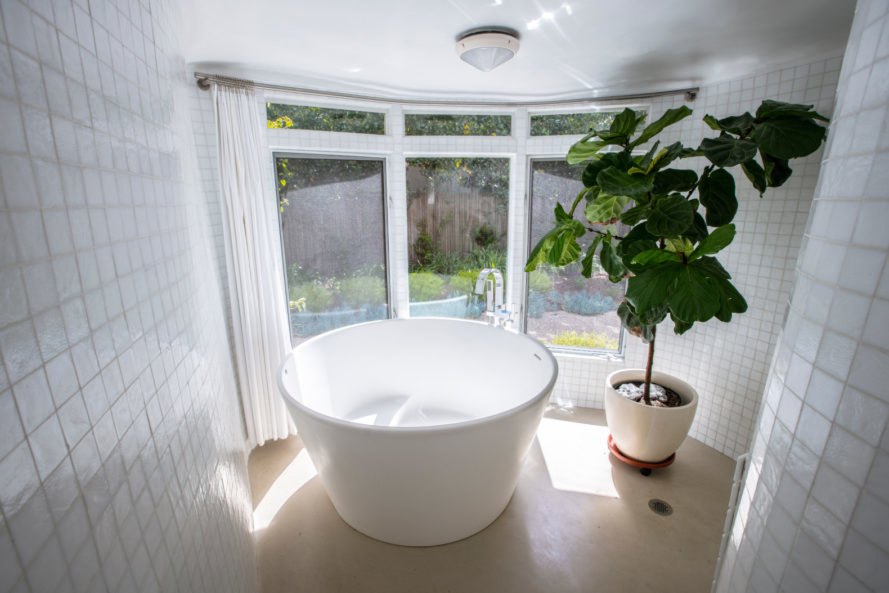 a white round bathtub with view of gardens