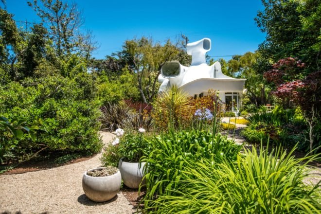 a unique white home behind landscaped gardens