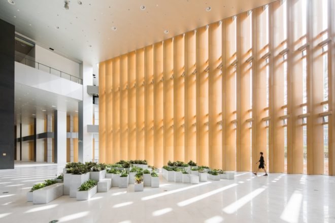 Lobby area with large clusters of plants in rectangular planters on the floor
