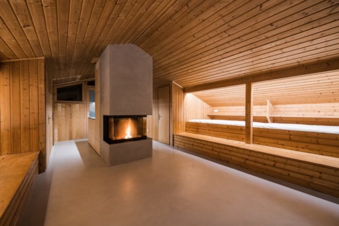 wood-lined room with two beds and central fireplace