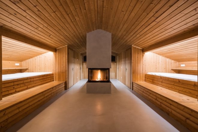 concrete fireplace in center of wooden room with beds on each wall