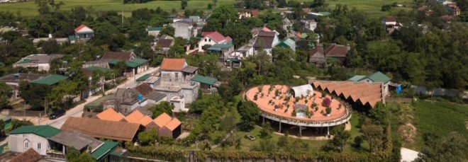 aerial view of plot of land with red-roofed buildings and greenery