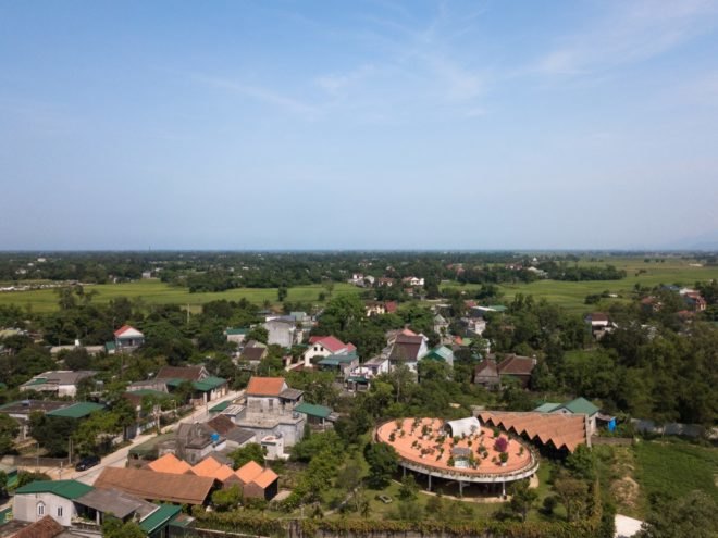 aerial view of plot of land with red-roofed buildings and greenery