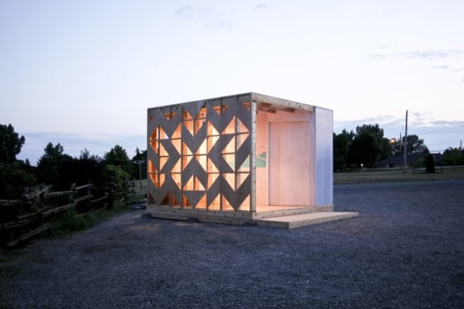 cubic wooden pavilion lit up at night