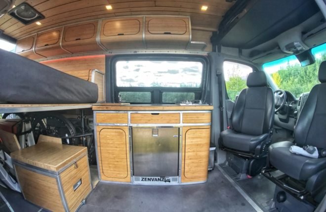 interior of converted van with bamboo cabinetry and a lifted bed