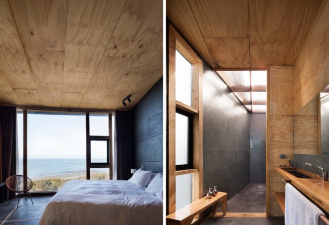 On the left, white bed near large window overlooking the sea. On the right, light wood bathroom.