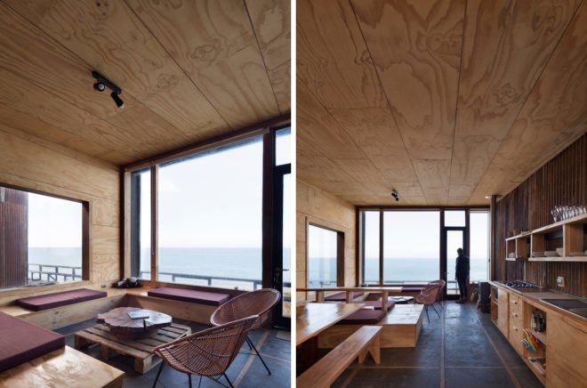 On the left, cushioned benches near window overlooking the sea. On the right, wood benches and wood kitchen cabinets.
