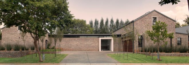 Brick farmhouse with small trees in front yard at dusk