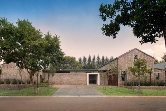 Brick farmhouse with small trees in front yard at dusk
