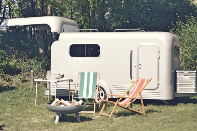 Two lawn chairs and a small fire pit in front of aluminum trailer