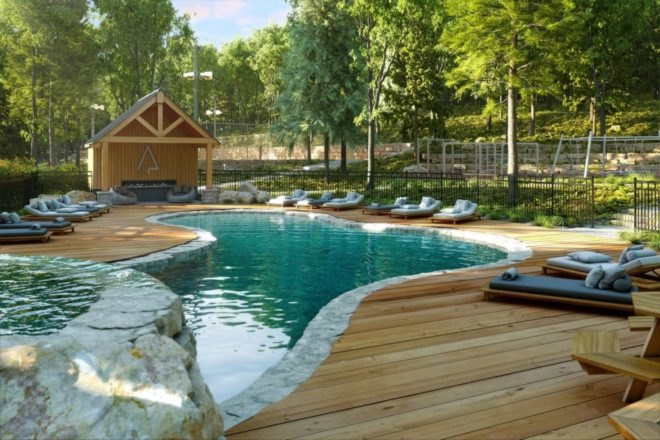 Curvy pool with wood decking and patio chairs surrounding the pool