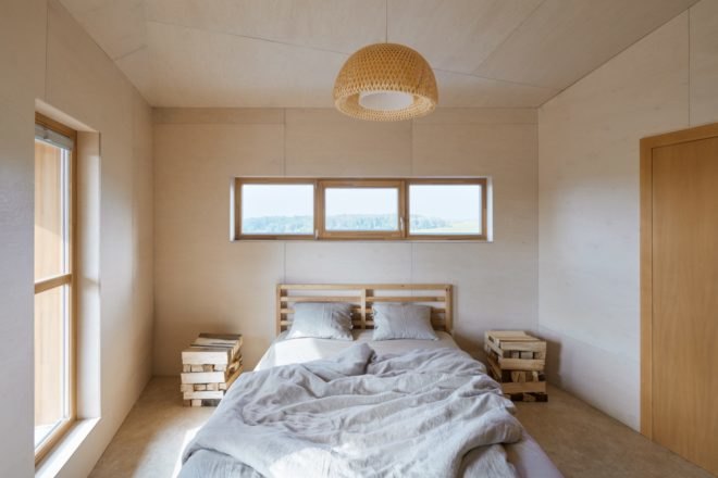 gray bed in a room lined in light wood