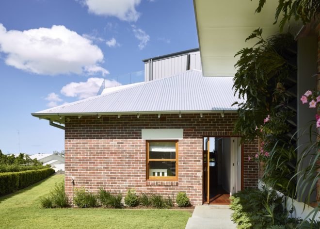 brick home with open door leading to grassy lot