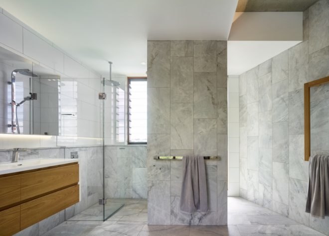 bathroom with marble tiled walls and floors and a wood and porcelain sink