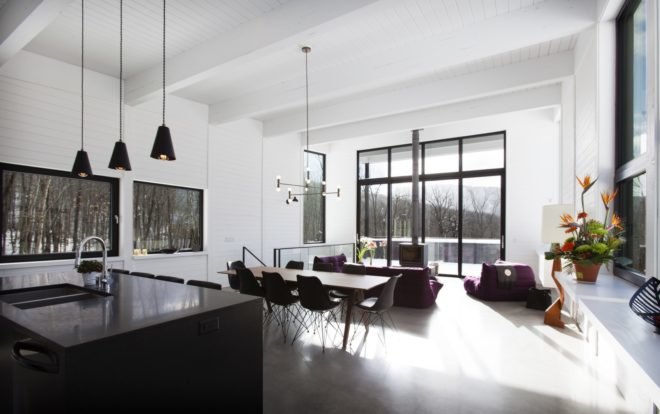 open plan room with black kitchen island, wood dining table and purple couches