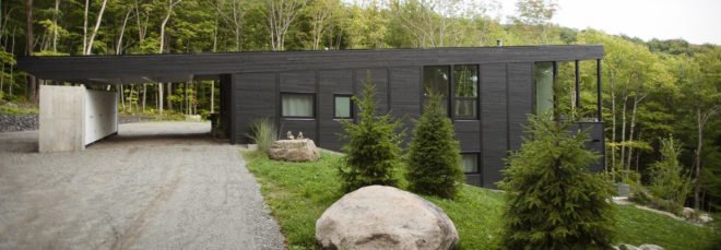cropped close-up of black timber home built into a grassy slope