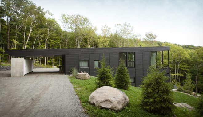 Black timber home built into a grassy slope