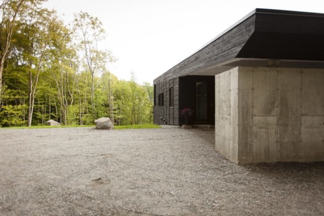 driveway and thick concrete wall on a black timber home