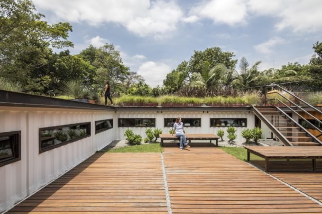deck with benches and stairs leading to green roof on top of a shipping container