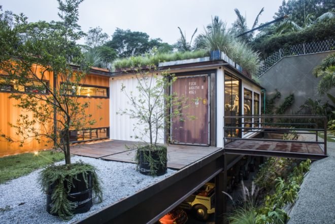 deck with potted plants leading to shipping container with a green roof