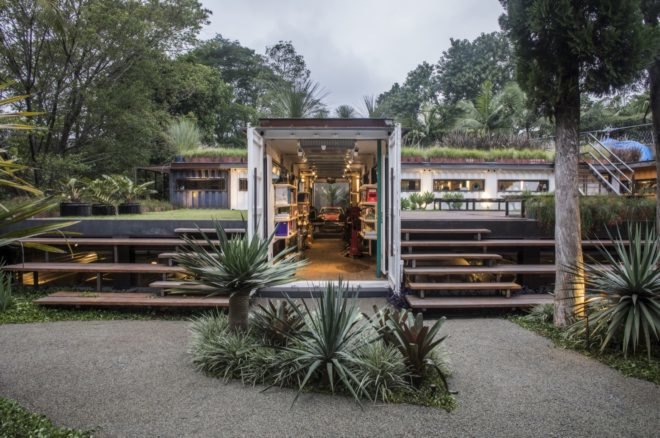 shipping containers topped with plants and filled with art