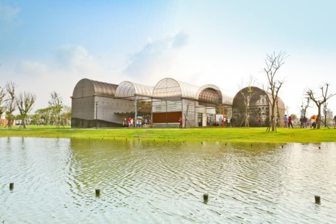greenhouses with rounded roofs in order of descending height with lake in foreground