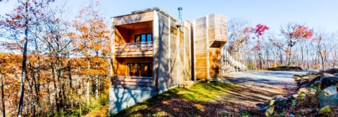 timber clad home on a hill in the forest in autumn