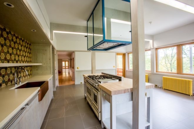 kitchen with white cabinets and timber countertop island with colorful backsplash