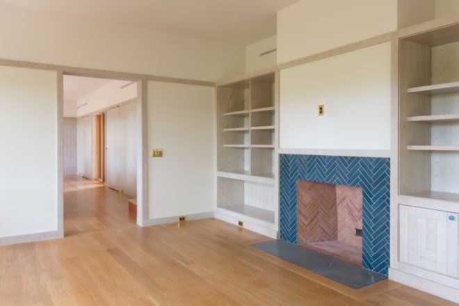 all-white room with built-in shelves and a blue tiled fireplace
