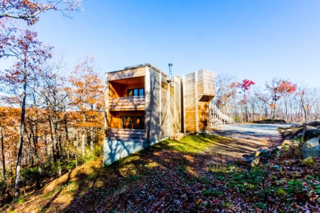 timber clad home on a hill in the forest in autumn