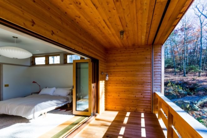 timber-lined balcony with doors opening to all-white bedroom