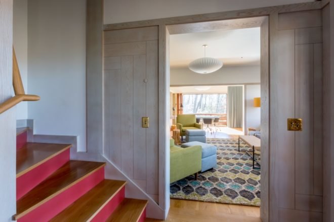 wood and red stairs next to lviing space with blue and green furniture