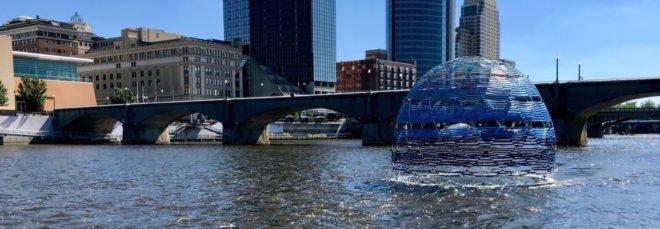 cropped close-up of blue dome floating on a river with skyscrapers in background
