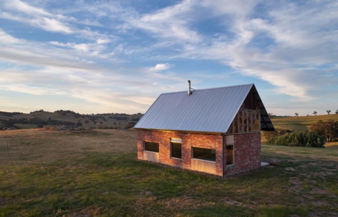 Small shed with brick exterior and gabled sheet metal roof