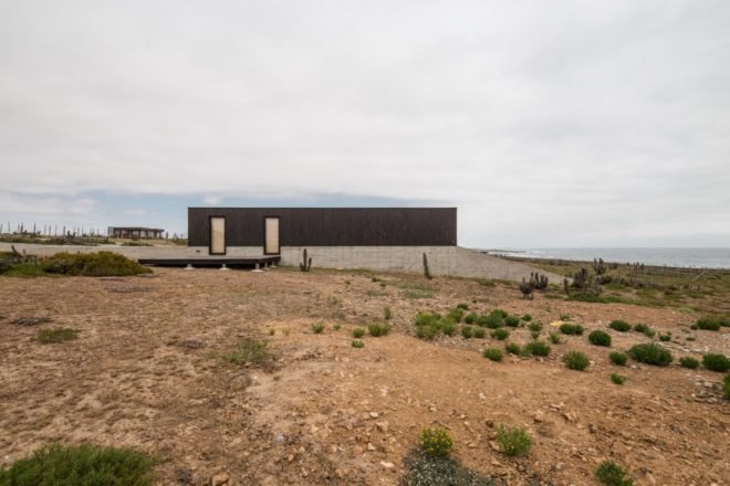 black timber and stone home set on a desert landscape