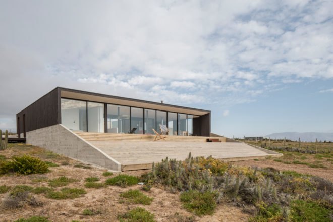 angled view of home with a glazed facade leading to a patio