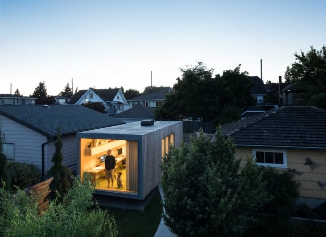 aerial shot of building with large building with large end window revealing man and dog peering outside